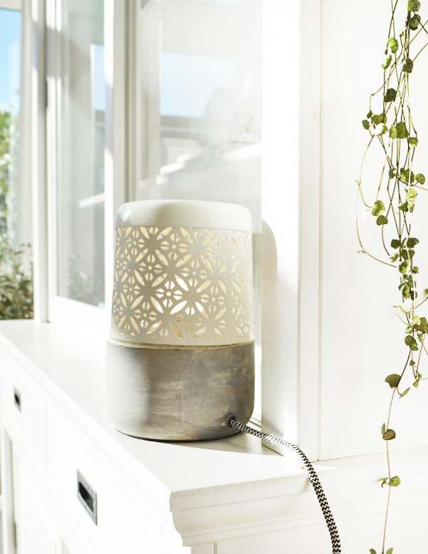 Der Lampenschirm ist beige und ruht auf einem grauen Holzsockel. Das Motiv schmckt die Wnde, sobald man es aufsetzt, und das macht die Lampe so attraktiv.
