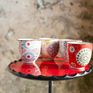 Vier grifflose Keramikbecher mit Blumenmotiven.