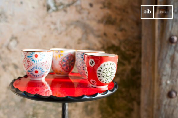 Vier grifflose Keramikbecher mit Blumenmotiven.