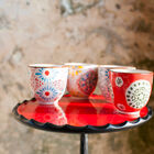 Quatre tasses sans anse en céramique aux motifs floraux.