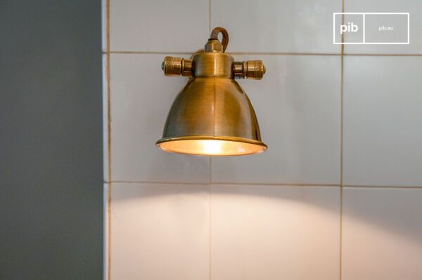 L'abat-jour en laiton satiné diffuse une lumière douce et concentrée.