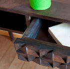 De combinatie van donkere houten poten een lade met geometrische reliëfs geven de Balis houten