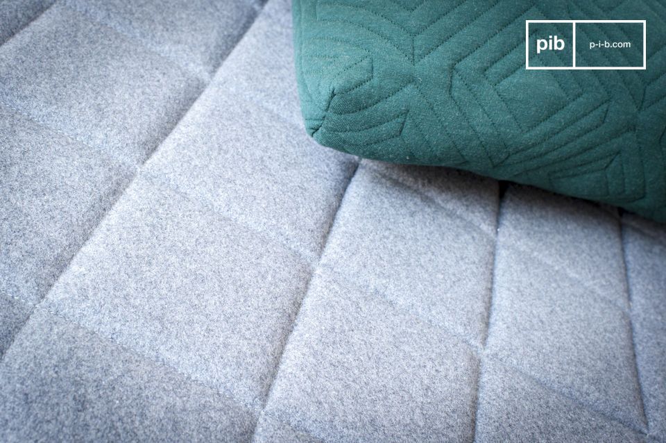 Le relief créé par le capitonnage du matelas capte la lumière et rompt avec la neutralité de l'ensemble.