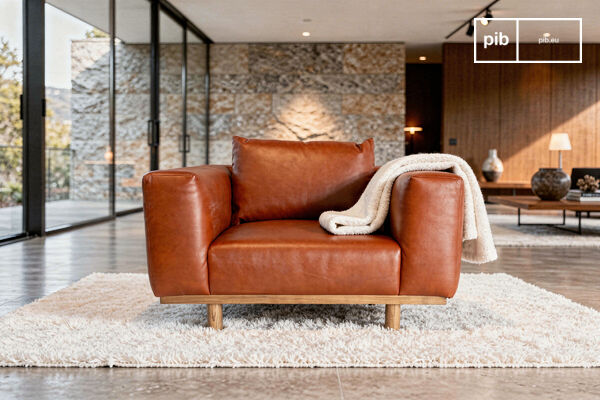 Deze ruime fauteuil rust op een zichtbare structuur van massief eikenhout