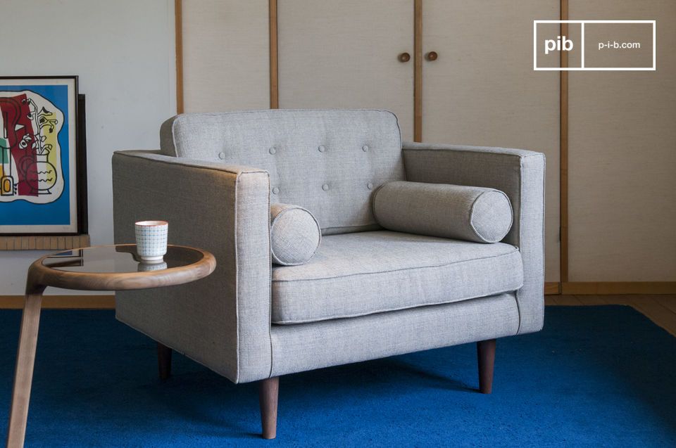 Le fauteuil arbore de lignes droites adoucies par deux coussins cylindriques.