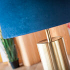 Cilindrische lampvoet in geborsteld messing heeft een gouden tint.