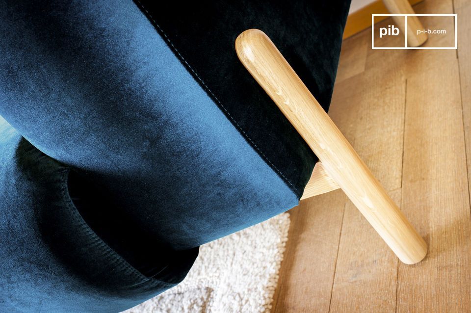 Le velours bleu profond contraste avec le bois clair du piètement.