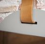 Le miroir est suspendu par une épaisse lanière de cuir clair.