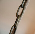 Eine Metallkette und das geflochtene Stromkabel verbinden die Leuchte mit einer Metallabdeckung.