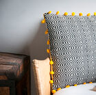 Elegant zwart-wit kussen met gele pompons.