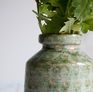 Die Vase ist mit kleinen, leicht orangefarbenen Punkten besetzt.