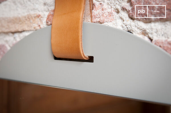 The mirror is suspended by a thick strip of light leather.