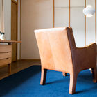 Entirely made out of leather it has thin armrests whose curve is particularly aesthetic