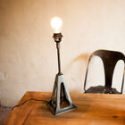 Lampe mit pyramidenförmigen Füßen, die von einer Metallstange durchbohrt werden.