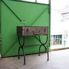 Its base formed by two semi-circles supports a top representing a suitcase.