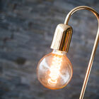 The long filament bulb is supported by a brushed golden brass rod.
