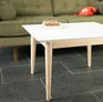 Quadratischer Couchtisch mit weißer Platte und Holzsockel.