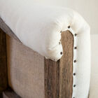 The white fabric is nicely studded on the wooden armrests.