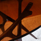 Its smoked glass tabletop rests on a sculptural base that evokes intertwined natural lines