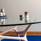 Its tempered glass tabletop rests on a sculpted base reminiscent of intertwined branches