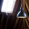 La silhouette en dôme évoque les luminaires industriels du XXe siècle, revisités en version noire mate.