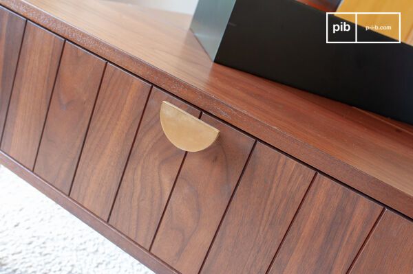 La poignée en métal doré en demi-lune contraste avec le graphisme de la façade du tiroir.