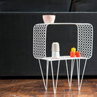 Une petite table d'appoint en métal ajouré blanc, alliant légèreté visuelle et lignes modernes arrondies.