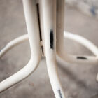 El taburete tiene un pie blanco patinado con curvas.