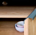 The handles offer an aesthetic contrast with the light oak.