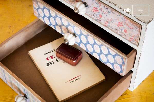 Dit kleine meubelstuk heeft drie verschillende lades, elke voorzien van een ander bloemenmotief