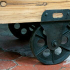 the table is made of thick varnished wood, and mounted on cast iron wheels.